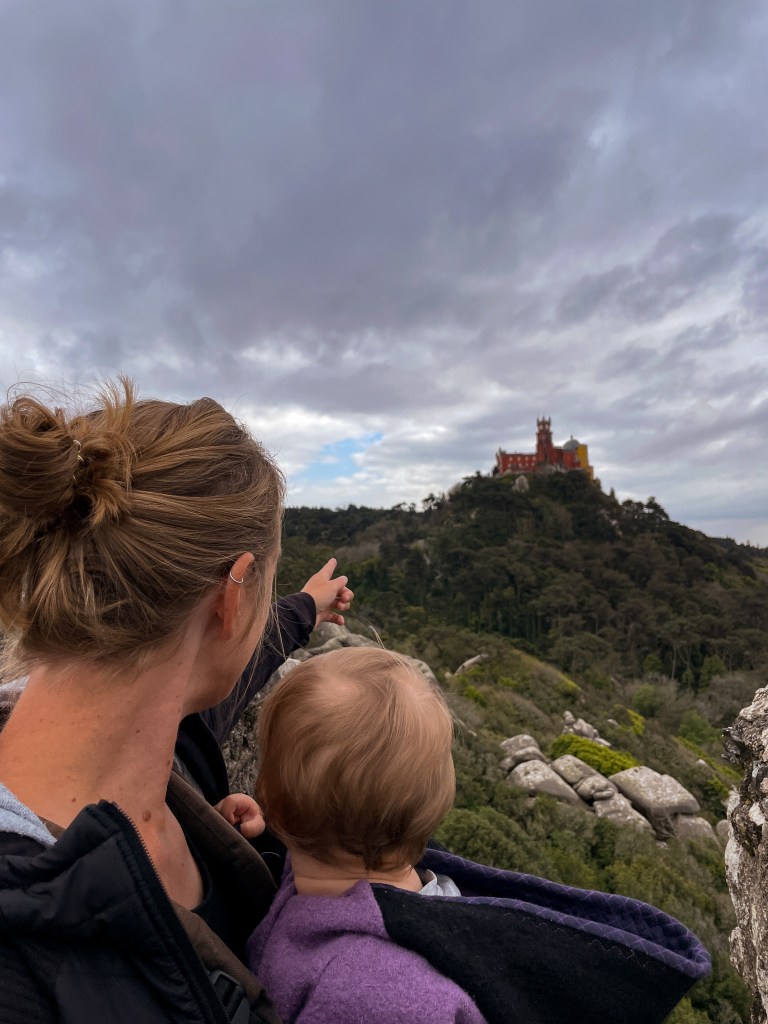 Palacio Nacional da Pena, Hotspot in Sintra, Märchenschloss auf einem Berg. Frau, die Mama mit Baby in der Trage blicken auf das Märchenschloss. 